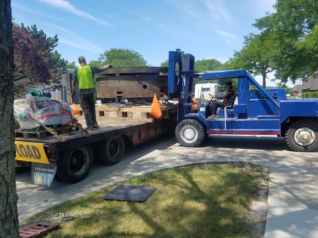 60-80,000 lb rigger lift carrying a machine base out for loading