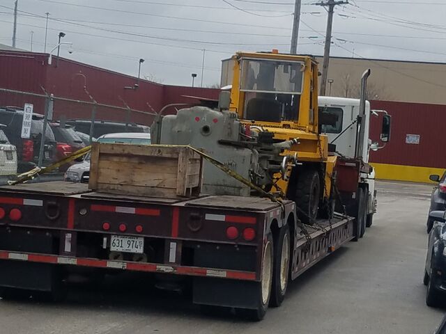 Milling machine and crate chained down on the lowboy
