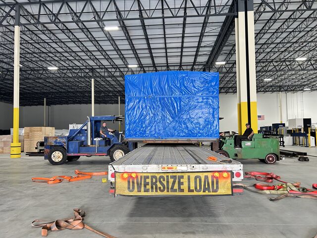 Our trailer backed inside a Schaumburg laser shop, bringing in a wrapped machine past the HSG cutters already running