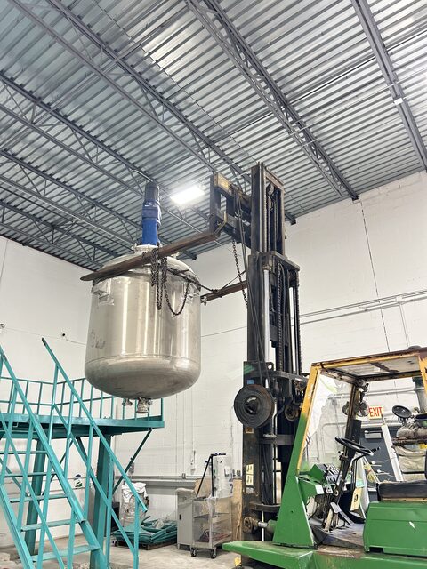 Lifting a stainless steel mixing vessel out on chains, indoors and under a low roof